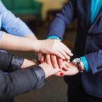 people-standing-office-holding-hands-together_23-2147650947